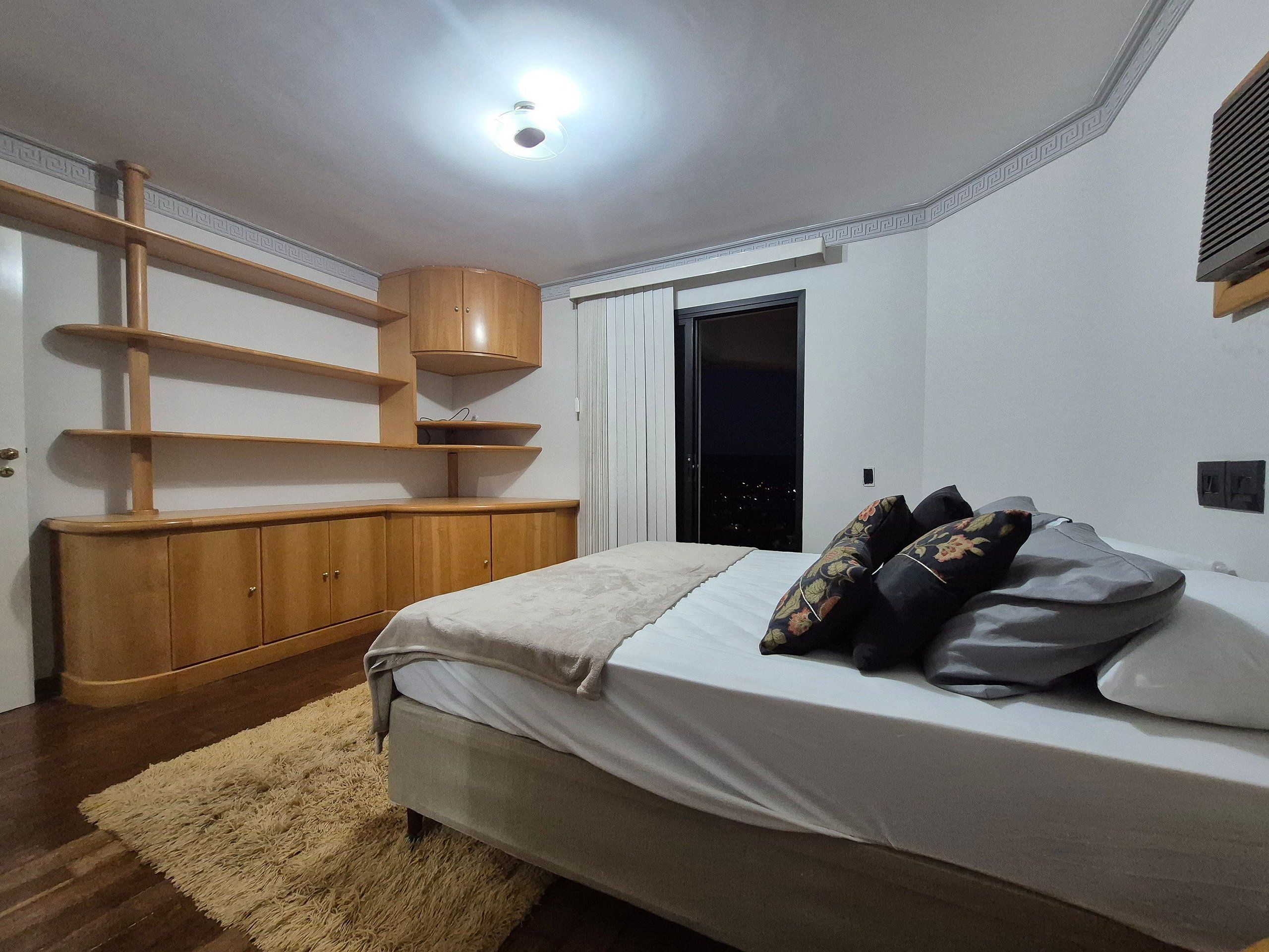 A bedroom with a bed, wooden furniture, a window, and a door.