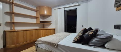 A bedroom with a bed, wooden furniture, a window, and a door.