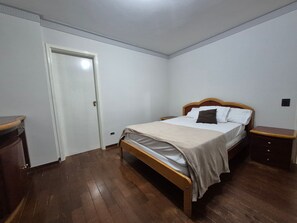 Un dormitorio con cama de madera, una mesita de noche y una puerta.