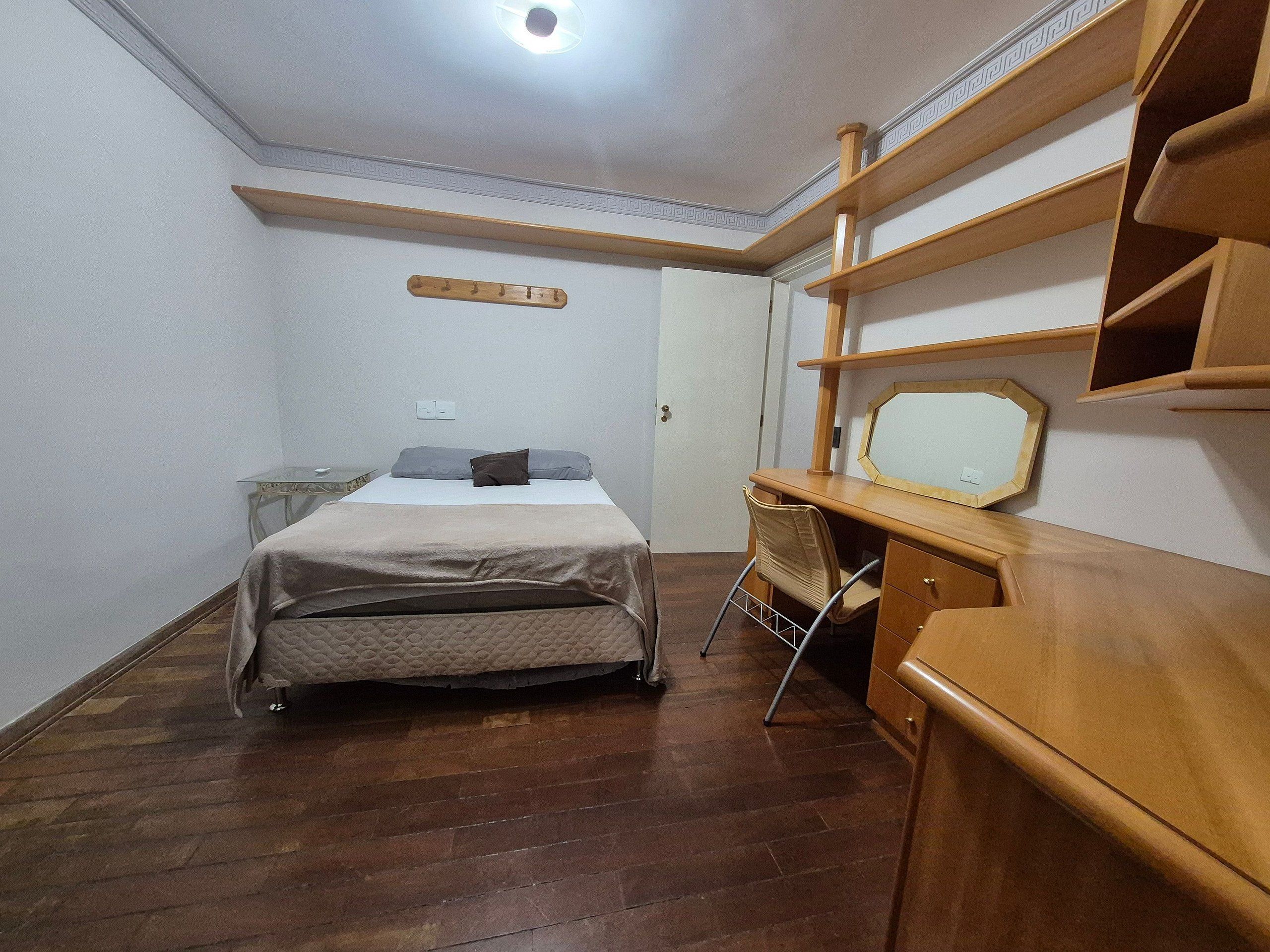 Een slaapkamer met een bed, een bureau en een stoel.