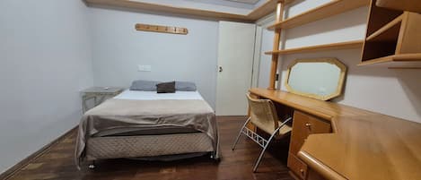 A bedroom with a bed, a desk, and a chair.