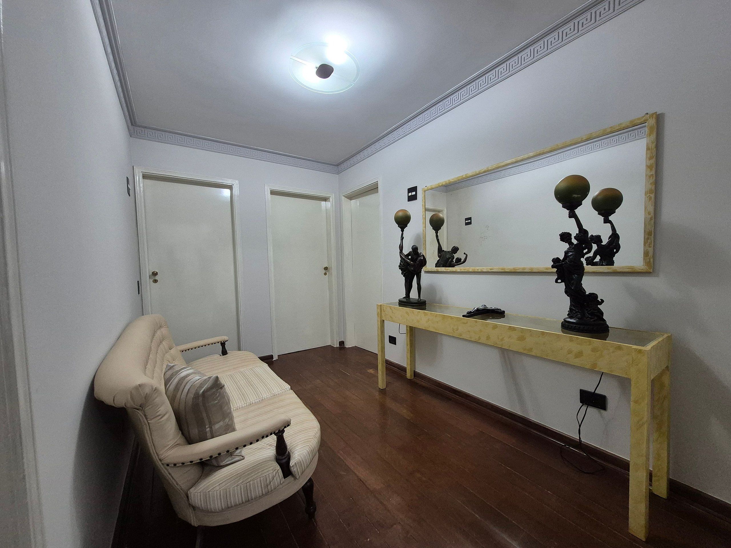 A hallway with a chair, a console table with a mirror, and three closed doors.