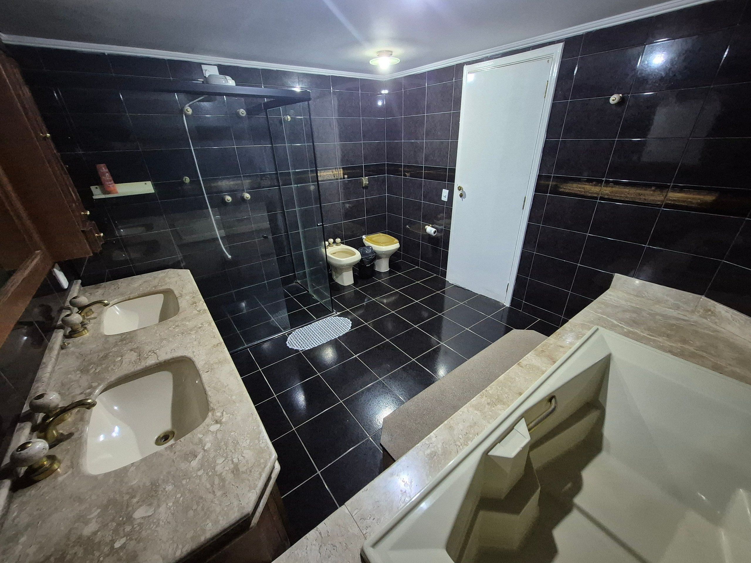 Une salle de bain avec deux lavabos, une baignoire, une douche et des toilettes.