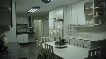 A kitchen with white cabinets, a dining table, chairs, and a flower vase.