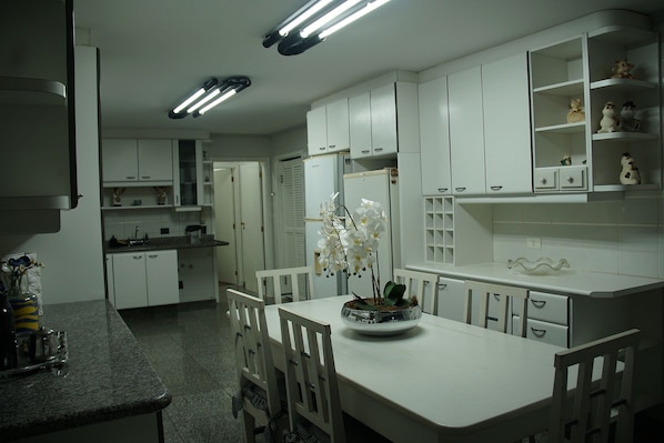 A kitchen with white cabinets, a dining table, chairs, and a flower vase.