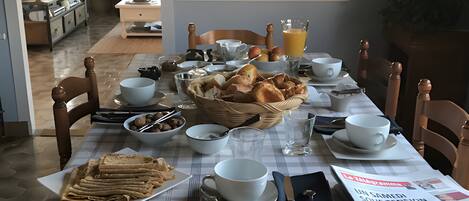 Une table à manger dressée avec des aliments pour le petit-déjeuner, notamment du pain, des œufs et des boissons.
