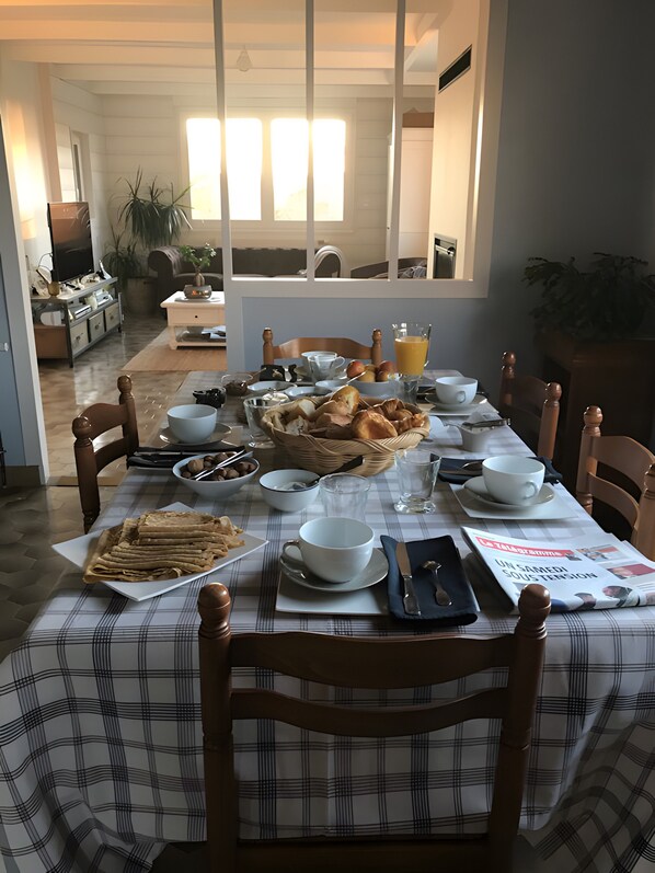 Une table à manger dressée avec des aliments pour le petit-déjeuner, notamment du pain, des œufs et des boissons.