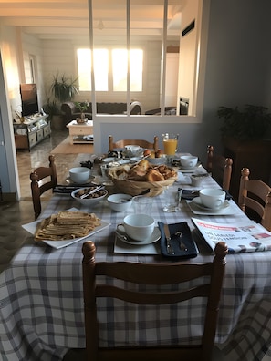 A dining table set with breakfast items, including bread, eggs, and beverages. - Chambre Poisson: Between Land and Sea (Lampaul-Guimiliau)