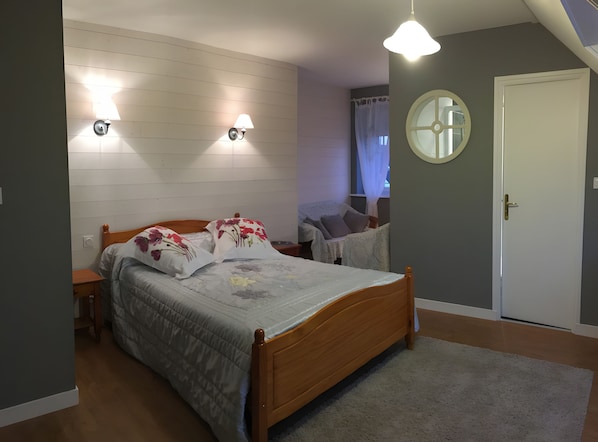 A bedroom with a wooden bed, two wall-mounted lamps, a round mirror, and a door. - Chambre Poisson: Between Land and Sea (Lampaul-Guimiliau)