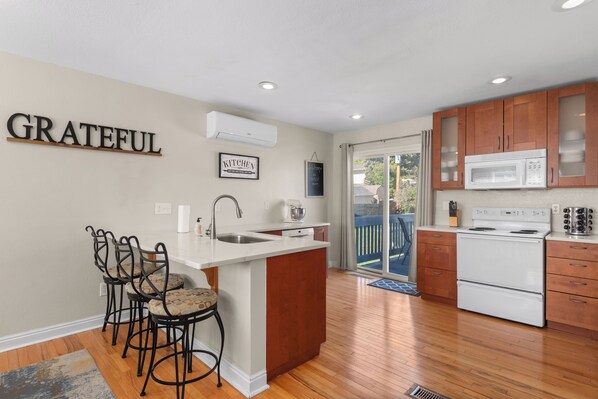 A kitchen with a central island, a sink, and a stove. There are wooden cabinets, a microwave, and a refrigerator.