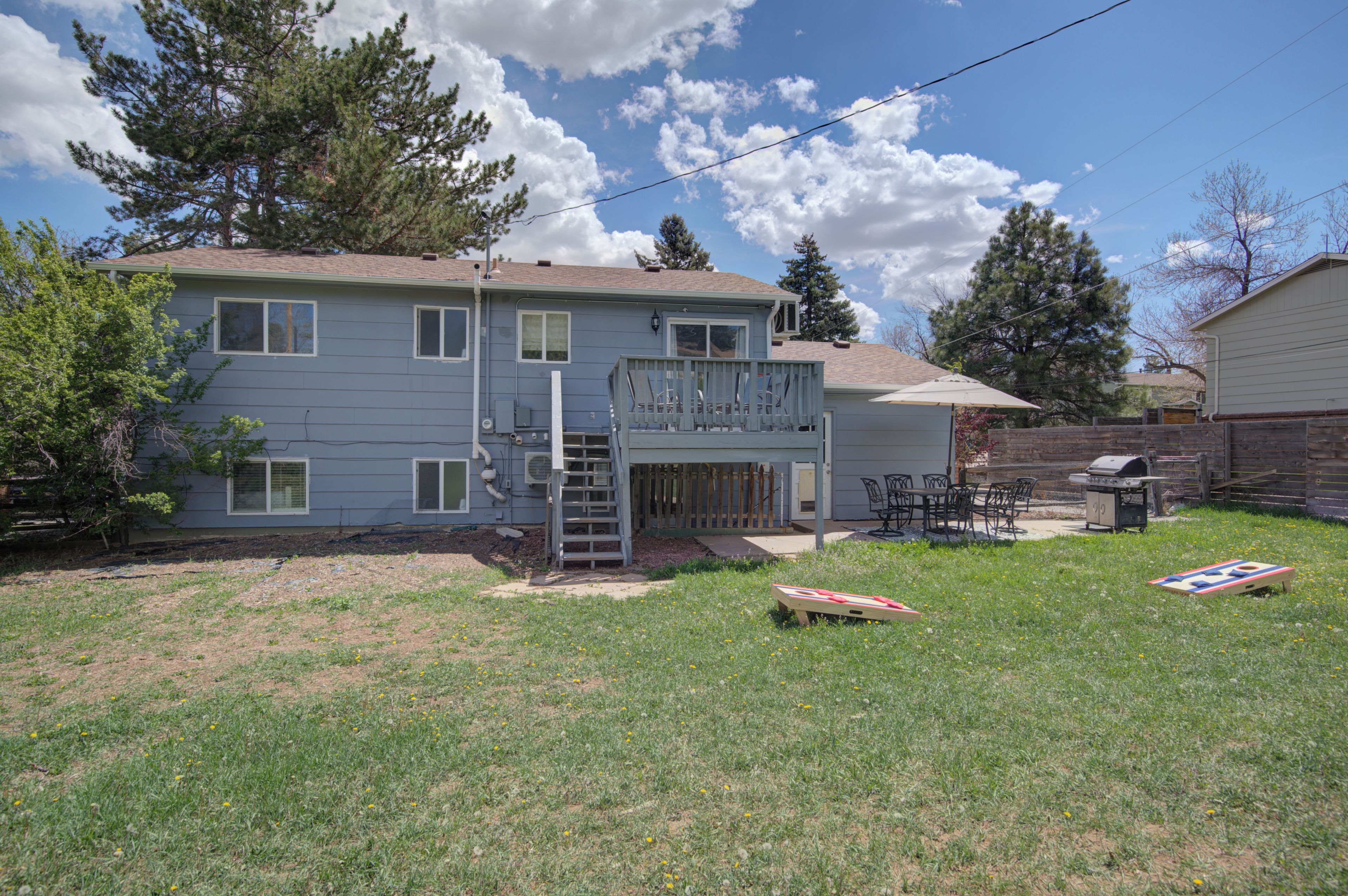 A two-story residential building with a front deck, a barbecue grill, and a small outdoor seating area.
