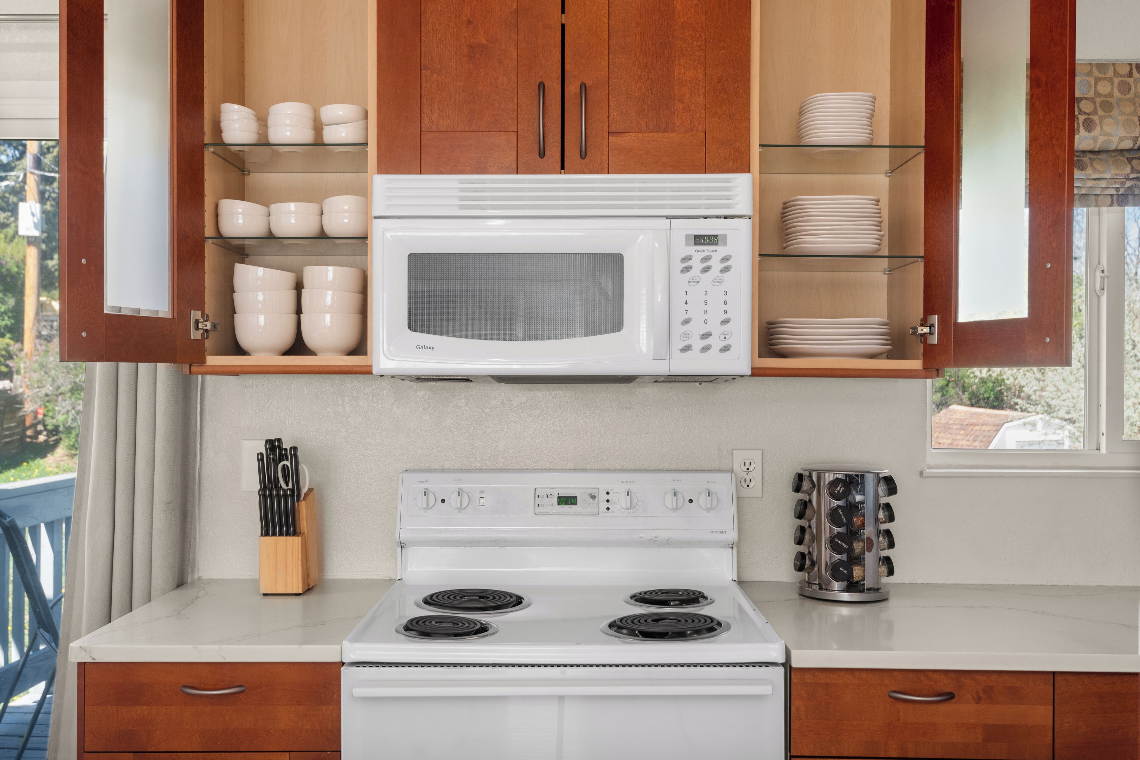 Una cocina con microondas blanco, estufa y armarios de madera.