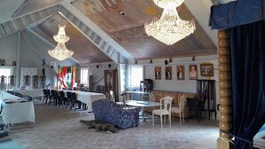Ein geräumiger Raum mit hoher Decke, Kronleuchtern, einem langen Tisch und mehreren Stühlen.