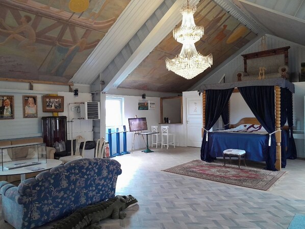 Una habitación con cama, un candelabro, un cuadro sobre caballete y un sofá.
