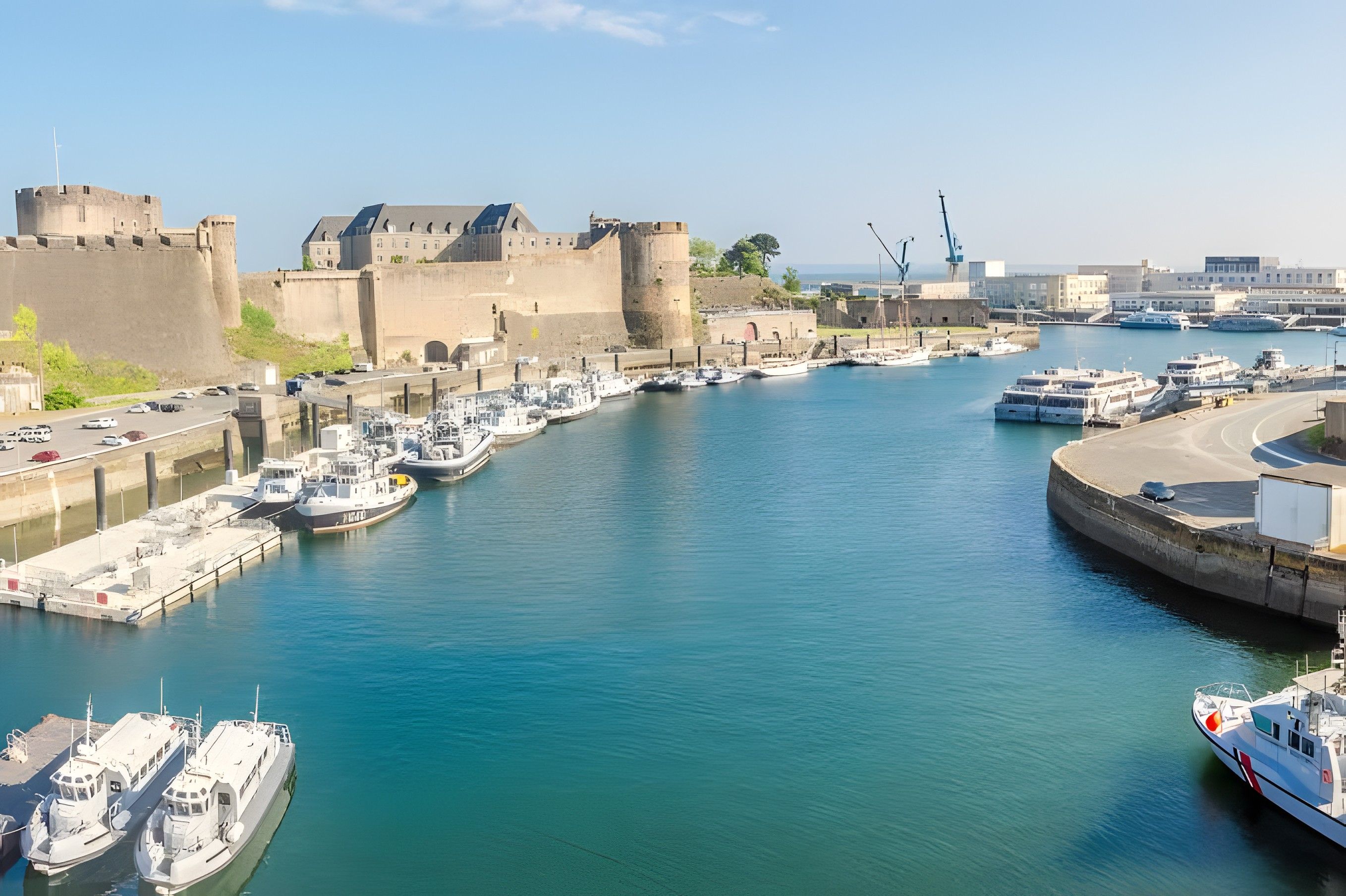 Un port où sont amarrés de nombreux bateaux, une structure fortifiée et un ciel dégagé.