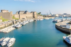 A harbor with multiple boats docked, a fortified structure, and a clear sky. - Chambre Bateau: between Brest, Landerneau, and the Bay of Morlaix (Lampaul-Guimiliau)