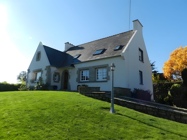 A two-story house with a sloped roof, a front entrance, and a well-maintained lawn. - Chambre Bateau: between Brest, Landerneau, and the Bay of Morlaix (Lampaul-Guimiliau)