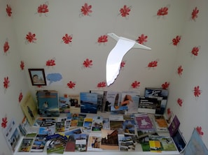 A room with a wall decorated with red floral patterns, a white bird-shaped object, and a collection of books and magazines on the floor. - Chambre Bateau: between Brest, Landerneau, and the Bay of Morlaix (Lampaul-Guimiliau)