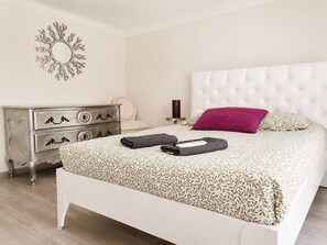 Ein Schlafzimmer mit einem Bett, einer Kommode, einem Spiegel und einer Wanddekoration.