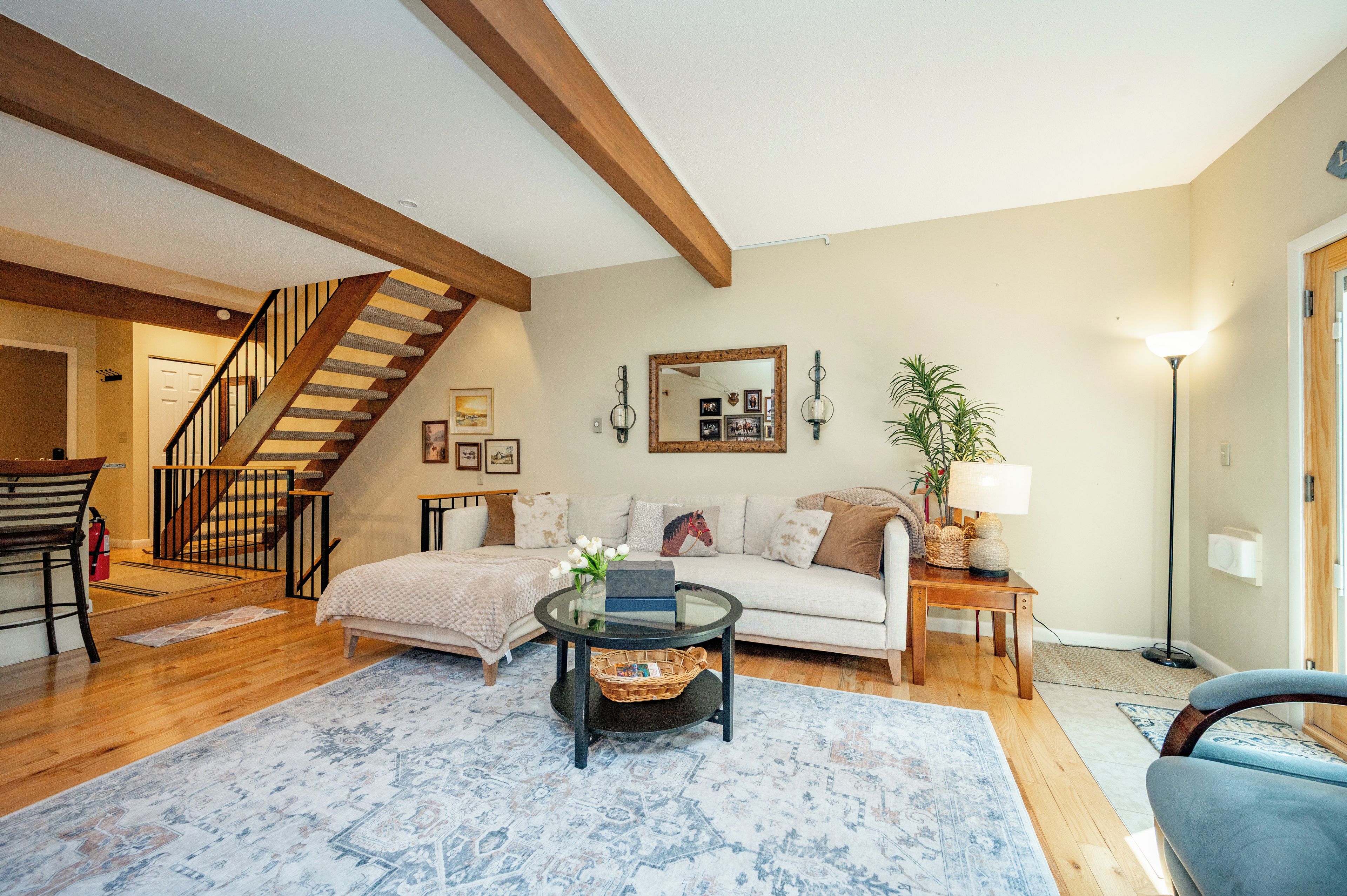 A living room with a staircase, a sofa, a coffee table, and a lamp.
