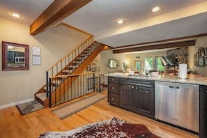 A kitchen with a wooden staircase, stainless steel appliances, and a stone accent wall. - New! Ski In/Out Home w/ Hot Tub! (McHenry)
