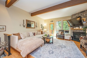 A cozy living room with a fireplace, a sofa, a coffee table, and a television. - New! Ski In/Out Home w/ Hot Tub! (McHenry)