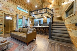 Ein Holzhaus-Interieur mit Sofa, Essbereich, Küche und einer Treppe.