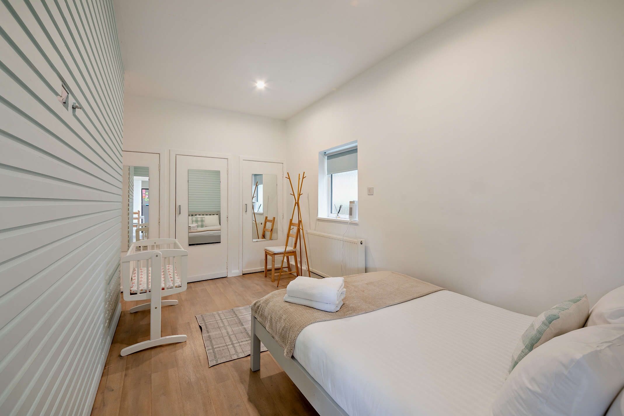 Une chambre à coucher avec un lit, une chaise, une fen être et un radiateur.