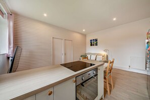 Eine moderne Küche mit Einbauherd, Backofen und einem Essbereich mit Tisch und Stühlen.
