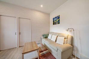 Ein modernes Wohnzimmer mit einer Couch, einem Holztisch, einer Stehlampe und einer Tür.