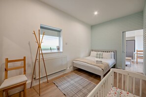 Une chambre à coucher avec un lit, un radiateur, une fenêtre, une chaise et un berceau.
