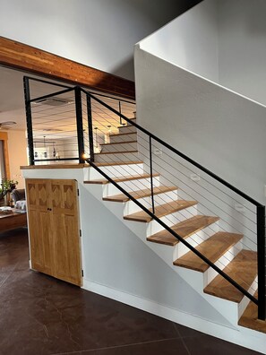 A staircase with wooden steps and a black railing, leading to a landing with a wooden door.
