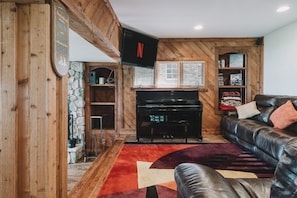 A cozy living room with a piano, a leather sofa, and a Netflix sign. - Long Lake Extended-Stay Furnished 30-Day+ Home (Ingleside)