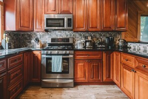 A kitchen with wooden cabinets, a stainless steel stove, a microwave, and a coffee maker.
