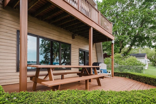 A wooden deck with a picnic table, a covered seating area, and a view of a lake.