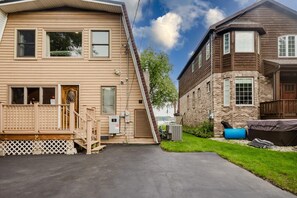 A two-story house with a front deck, a garage, and a backyard with a barbecue grill.