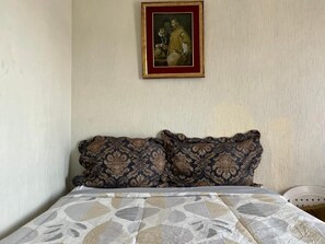 A bed with a patterned bedspread and two decorative pillows.
