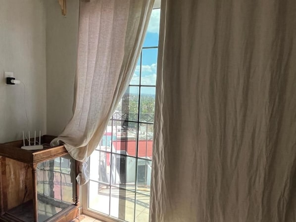 A room with a large window, a wooden cabinet with a glass top, and a power outlet on the wall.