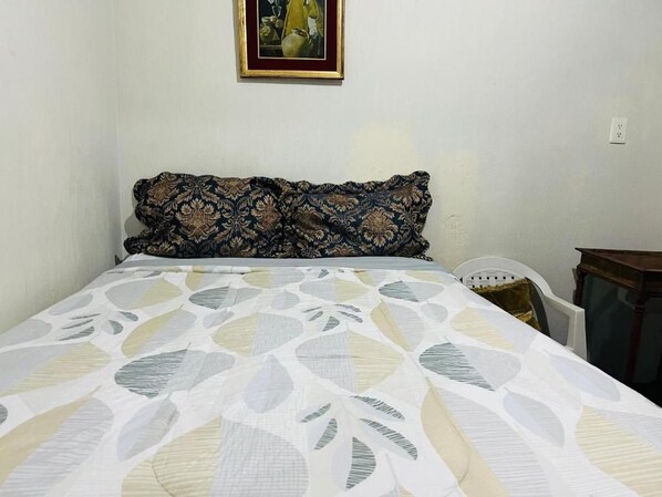 A single bed with a patterned bedspread and two decorative pillows.