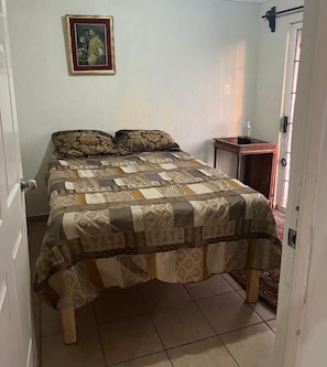Un dormitorio con cama, una mesita de noche y una puerta.