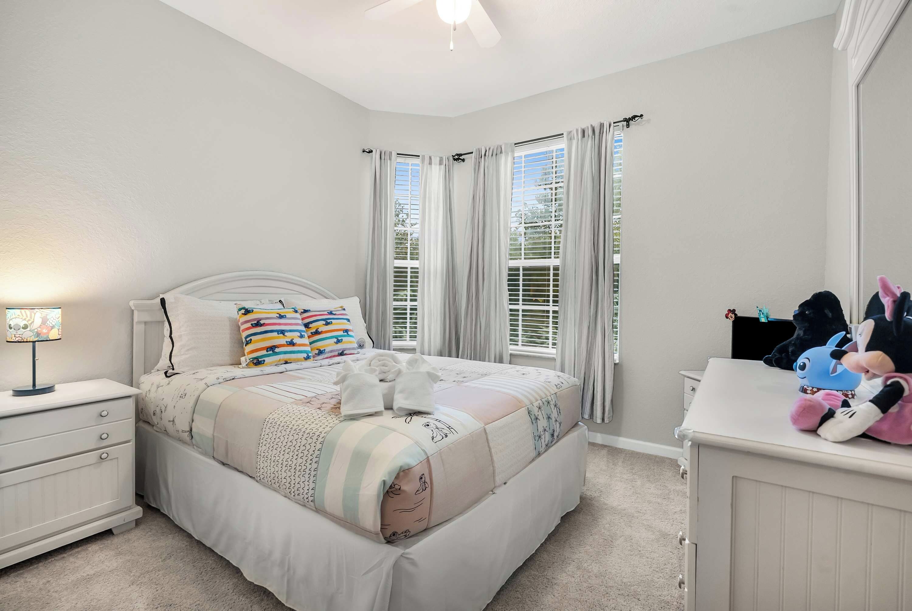 A bedroom with a bed, bedside tables, a lamp, and a dresser.