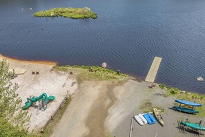 Een strandgebied met een klein eiland, een zandstrand, een speeltuin en diverse boten.