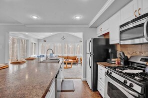 Een moderne keuken met een centraal eiland, roestvrijstalen apparatuur en een eethoek met een bank en tafel.