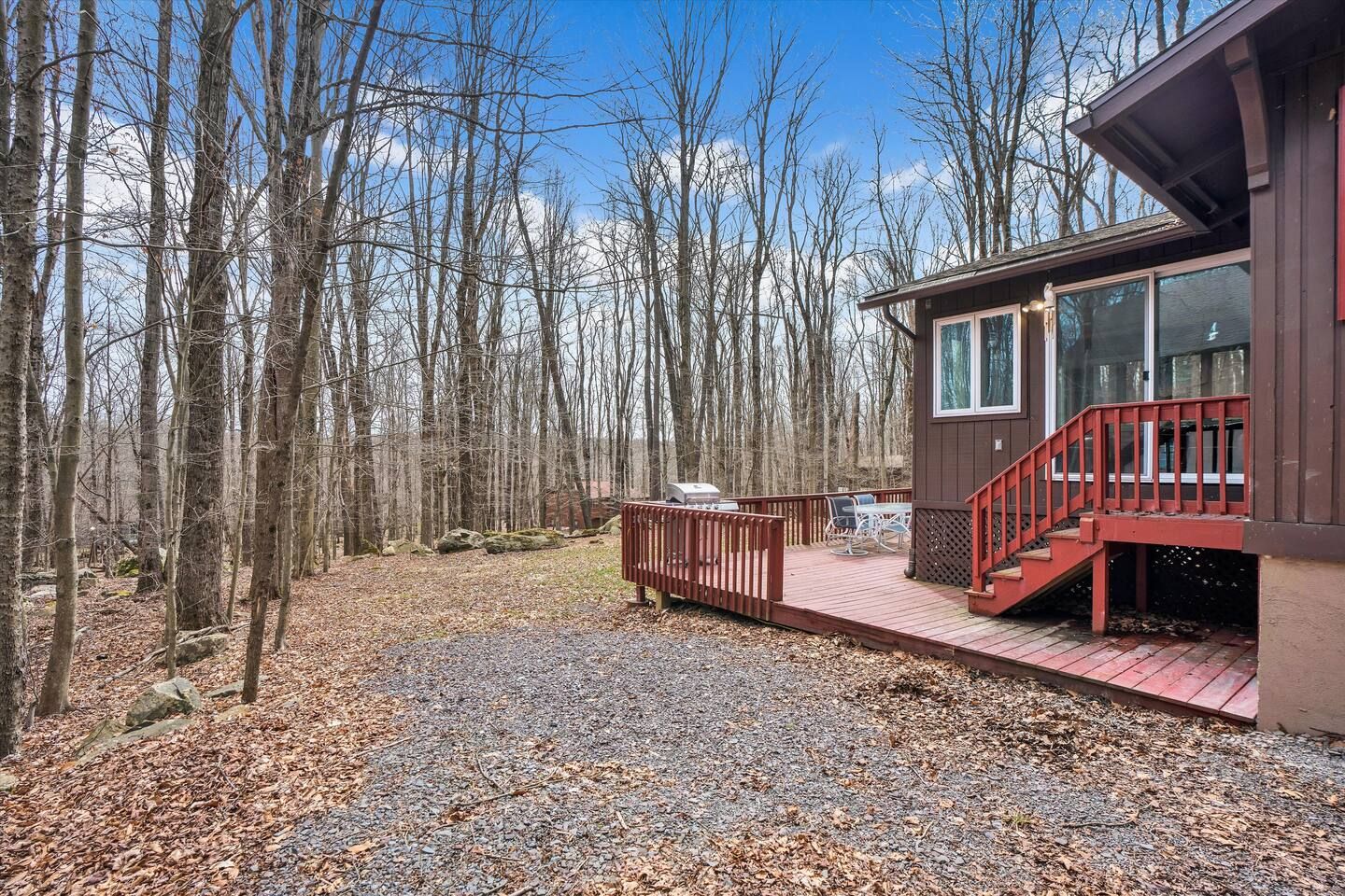 Een chalet met terras, omgeven door bos.