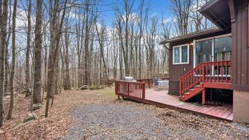 Een chalet met terras, omgeven door bos.