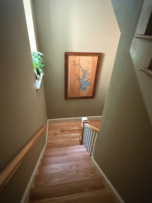 A wooden staircase with a radiator at the bottom, a framed artwork on the wall, and a potted plant on the left. - Secluded Lake Norman Waterfront Luxury, 4BR, 5.5 Baths with Home Theater (Mooresville)