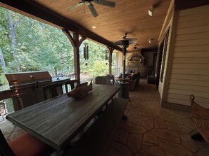 An outdoor patio with a wooden table, chairs, and a grill. - Secluded Lake Norman Waterfront Luxury, 4BR, 5.5 Baths with Home Theater (Mooresville)