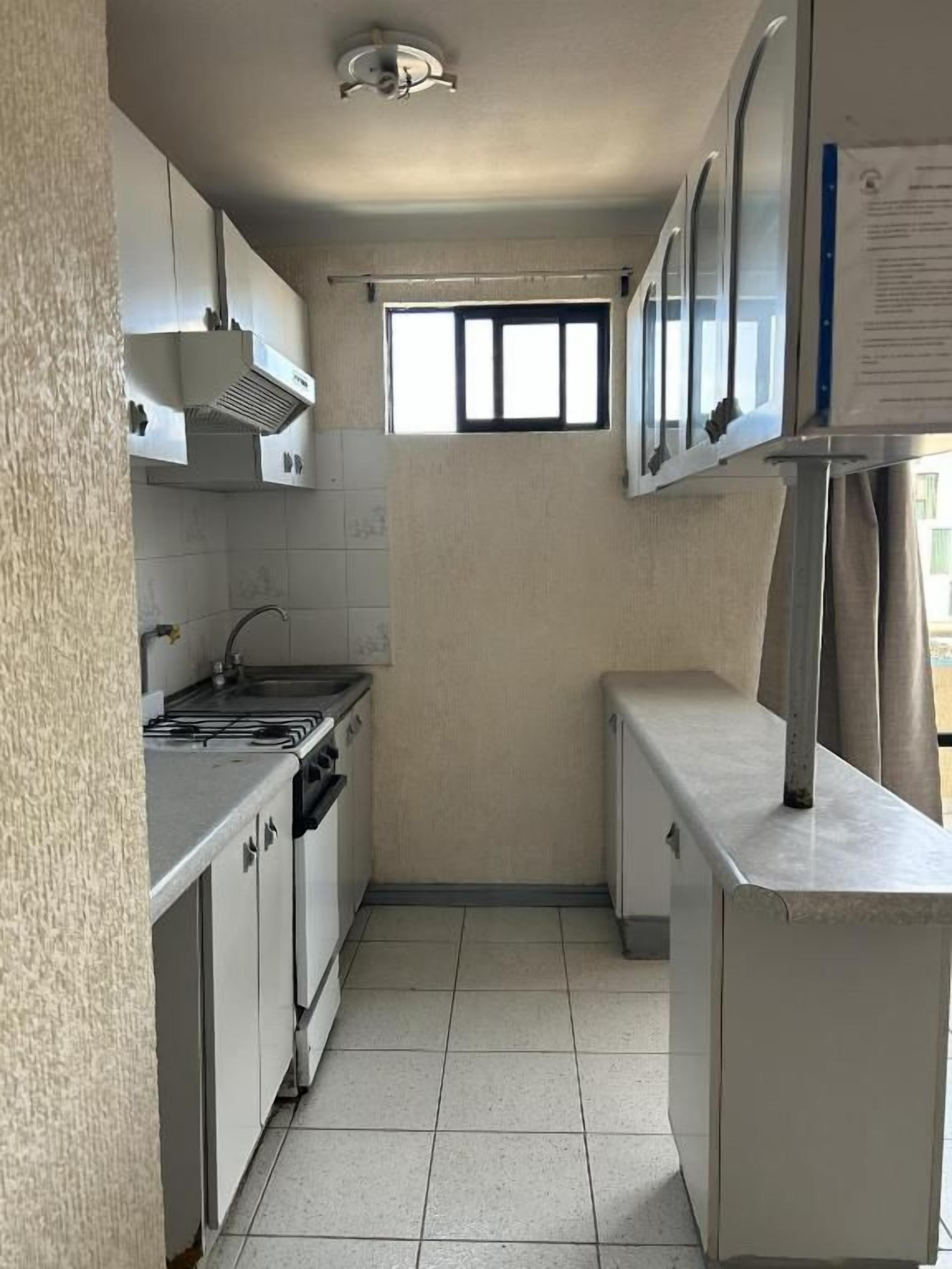 Una cocina compacta con estufa a gas, horno y un refrigerador pequeño.