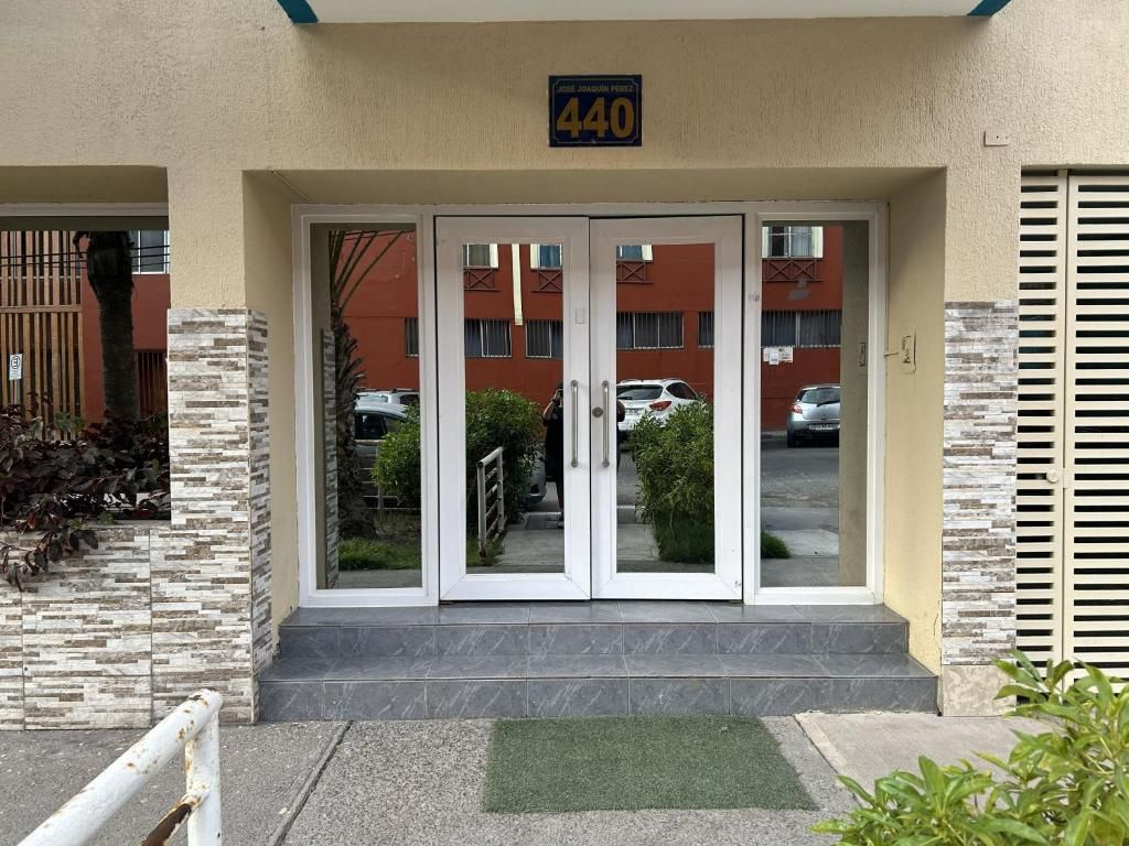 Entrada d'un edifici amb una porta doble, un senyal amb un número a dalt i un estriquet verd a l'entrada.