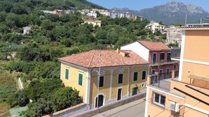 Un quartiere residenziale con edifici su una collina, una strada in primo piano e una montagna sullo sfondo.